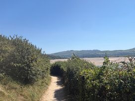 A path surrounded by bushes leading to sandy riverbank at The Quarterdeck in Borth-Y-Gest