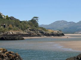 A beach scene with water, sand, rocks, and mountains at The Quarterdeck in Borth-Y-Gest