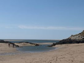 A beach with water and rocks at The Quarterdeck in Borth-Y-Gest