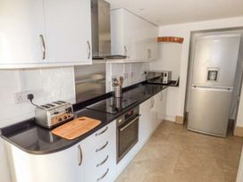 A kitchen with white cabinets black countertop stove toaster microwave and silver refrigerator at 1 Willow Cottage in Upton Upon Severn