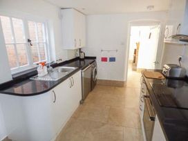 A kitchen with white cabinets black countertops a sink window and appliances at 1 Willow Cottage in Upton Upon Severn