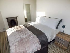 A bedroom with a double bed next to a nightstand with lamp and a small fireplace at 1 Willow Cottage in Upton Upon Severn