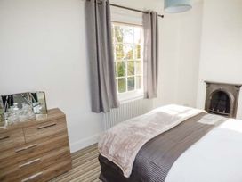 A bedroom with a bed near a window and a wooden dresser with mirrors at 1 Willow Cottage in Upton Upon Severn