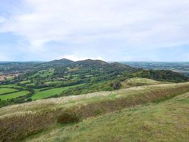 A grassy hill overlooking a patchwork of fields and forested hills in Upton Upon Severn