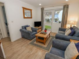 A living room with blue armchairs a wooden coffee table a television on a stand and curtains at Pierpont D1 Norton near Yarmouth