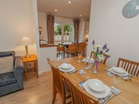 A dining area with a wooden table set with white dishes and a flower vase near a living area with a blue sofa and a lamp at Pierpont D1 in Norton near Yarmouth