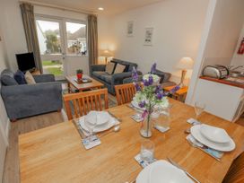 A dining table set with plates glasses and a flower vase with a living area with sofas table and TV at Pierpont D1 Norton near Yarmouth