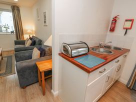 A small kitchen with a double sink and a bread box next to a living room with two armchairs and a side table at Pierpont D1 Norton near Yarmouth