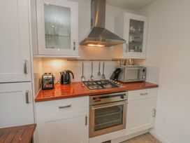 A kitchen with white cabinets a wooden countertop a gas stove an oven a microwave a toaster and a kettle at Pierpont D1 in Norton near Yarmouth