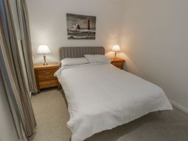 A bedroom with a bed between two wooden nightstands with lamps and a lighthouse picture above at Pierpont D1 Norton near Yarmouth