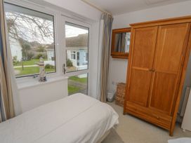 A bedroom with a bed near a window and glass door and a wooden wardrobe with a mirror on the wall at Pierpont D1 in Norton near Yarmouth