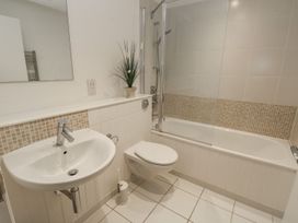 A bathroom with a sink, toilet, bathtub with shower, and a plant on the shelf at Pierpont D1 Norton near Yarmouth