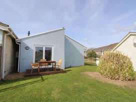 A backyard with a wooden deck with a table and chairs by a blue house at Pierpont D1 Norton near Yarmouth