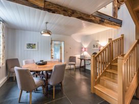 A dining area with a round wooden table and chairs near wooden stairs at Tan Llan in Llanelltyd near Dolgellau