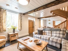 A living room with a plaid sofa wooden coffee table flowers on a side table and visible wooden stairs at Tan Llan in Llanelltyd near Dolgellau