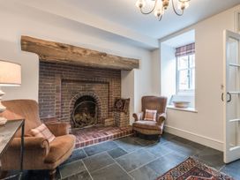 A sitting room with two armchairs a brick fireplace and a window at Tan Llan in Llanelltyd near Dolgellau