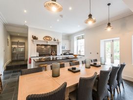 A kitchen and dining area with a wooden dining table and wicker chairs at Tan Llan in Llanelltyd near Dolgellau