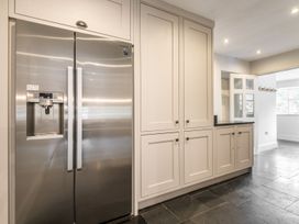A kitchen with a stainless steel refrigerator and white cabinetry on a tiled floor at Tan Llan in Llanelltyd near Dolgellau
