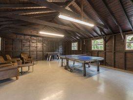 A game room with a ping pong table foosball table armchairs and small tables at Tan Llan in Llanelltyd near Dolgellau