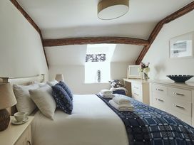 A bedroom with a bed folded towels and blue patterned bedding near wooden beams and white furniture at Tan Llan in Llanelltyd near Dolgellau