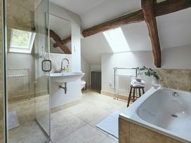 A bathroom with a bathtub a sink a glass shower and wooden beams at Tan Llan in Llanelltyd near Dolgellau