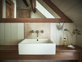 A bathroom sink with wall-mounted taps a mirror and toiletries at Tan Llan in Llanelltyd near Dolgellau