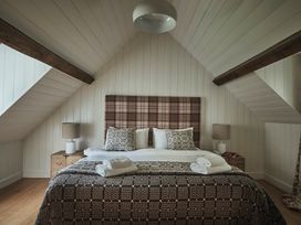 A bedroom with a bed with patterned pillows and blankets and bedside tables with lamps at Tan Llan in Llanelltyd near Dolgellau