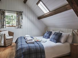 A bedroom with a double bed two blue patterned cushions stacked towels wicker chair and windows at Tan Llan Llanelltyd near Dolgellau