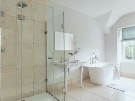 A bathroom with a glass shower enclosure sink with taps flower vase freestanding bathtub and window at Tan Llan in Llanelltyd near Dolgellau