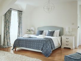 A bedroom with a double bed with patterned bedding two bedside tables with lamps and a window with curtains at Tan Llan in Llanelltyd near Dolgellau
