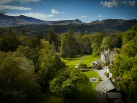 A large property with surrounding trees and lawns and distant mountains at Tan Llan in Llanelltyd near Dolgellau