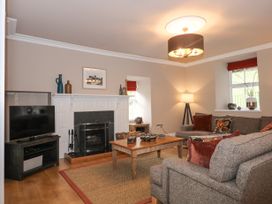 A living room with a fireplace a television a wooden coffee table and two sofas at Tan Llan in Llanelltyd near Dolgellau