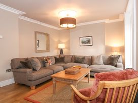 A living room with a corner sofa a wooden coffee table and a cushioned wooden chair at Tan Llan in Llanelltyd near Dolgellau