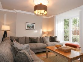 A living room with a large sectional sofa a wooden coffee table lamps and a large window with a red bench at Tan Llan in Llanelltyd near Dolgellau