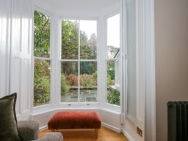 A bay window with an open window and a red bench below in a living room at Tan Llan in Llanelltyd near Dolgellau