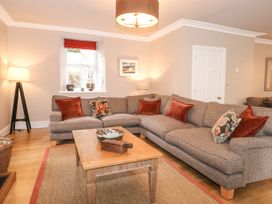 A living room with a large sectional sofa and wooden coffee table at Tan Llan in Llanelltyd near Dolgellau