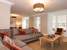 A living room with gray sofas red cushions wooden coffee table and armchair near large windows at Tan Llan in Llanelltyd near Dolgellau