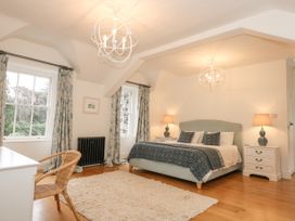 A bedroom with a bed bedside tables lamps a rug curtains and windows at Tan Llan in Llanelltyd near Dolgellau