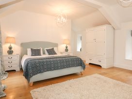 A bedroom with a double bed bedside tables with lamps a wardrobe and a rug on wooden floor at Tan Llan in Llanelltyd near Dolgellau