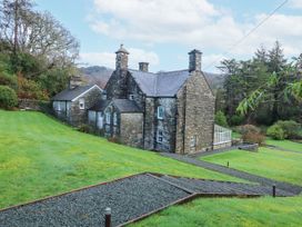 A stone house with chimneys surrounded by grass and trees at Tan Llan in Llanelltyd near Dolgellau
