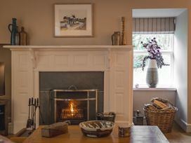A living room with a fireplace and flowers in a vase at Tan Llan in Llanelltyd near Dolgellau