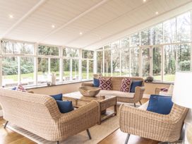 A conservatory with wicker furniture and a coffee table at Tan Llan Llanelltyd near Dolgellau