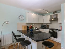 A kitchen with bar stools and appliances at 1 Oakley Wharf in Porthmadog