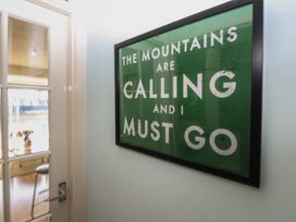An entryway with a sign reading the mountains are calling at 1 Oakley Wharf Porthmadog