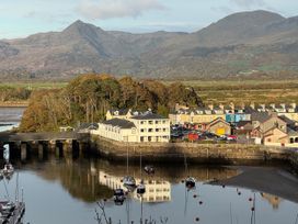 A view of a harbor with boats and buildings beside mountains at River's Edge Penthouse in Porthmadog