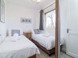A bedroom with two single beds a window and a wooden bedside cabinet at Cove View in Ilfracombe
