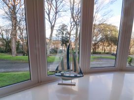 A model sailboat on a window sill with a view of trees and grass outside at Cove View in Ilfracombe