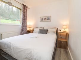 A bedroom with a bed two bedside tables with lamps a window and a picture on the wall at Cove View in Ilfracombe