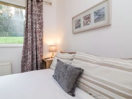 A bedroom with striped pillows and a bedside table with a lamp and a window at Cove View in Ilfracombe
