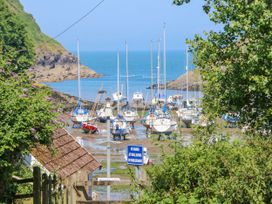 A small harbor with sailboats resting on muddy ground near rocky coastline surrounded by greenery at Cove View in Ilfracombe